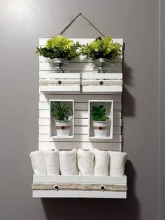 a white shelf with two potted plants on top of it next to a gray wall