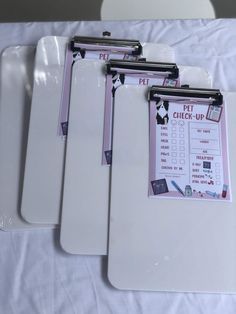 three white cutting boards sitting on top of a table with clipboards attached to them