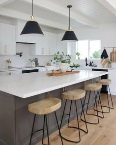 a kitchen island with four stools in front of it and three lights hanging from the ceiling