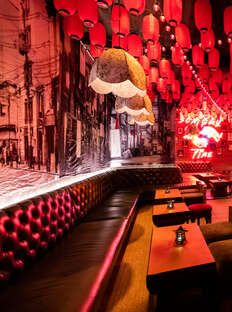 the interior of a restaurant with red lights hanging from the ceiling and booths lined up against the wall