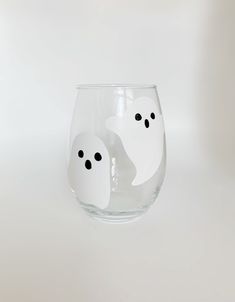 two ghost glasses sitting on top of a white table next to each other with eyes drawn on them