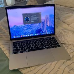 an open laptop computer sitting on top of a bed