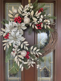 a christmas wreath on the front door with holly, berries and silver mistlet leaves