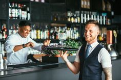 a man holding a tray with a cake on it in front of a bar counter