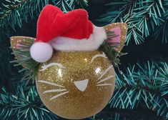 an ornament with a cat's head on it hanging from a christmas tree