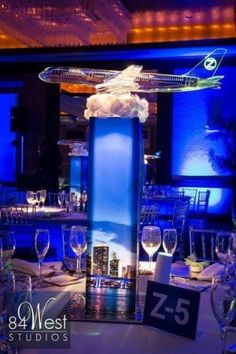 a table set up with wine glasses, plates and silverware in front of a blue lit room