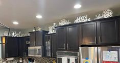 a kitchen with black cabinets and stainless steel appliances in the center is decorated with snowflakes