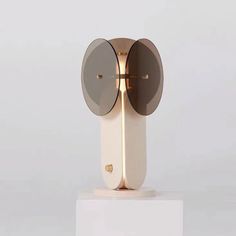 a white and gold clock with two mirrors on it's face sitting on a pedestal