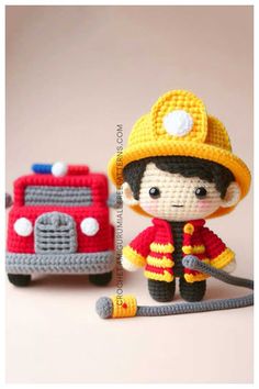 a crocheted fireman doll next to a toy truck