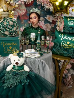 a woman sitting at a table with a teddy bear in front of her, surrounded by green and gold decorations