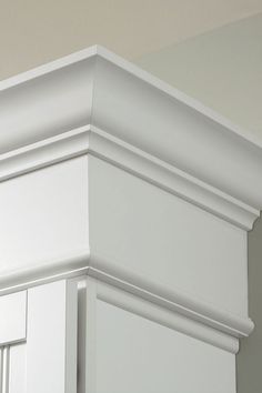 the corner of a white kitchen cabinet with molding on it's sides and bottom