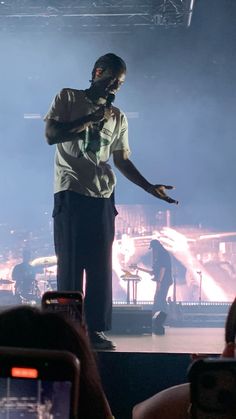 a man standing on top of a stage with his hands out in front of him