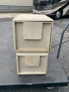 an old white box sitting on top of a black platform in front of a truck