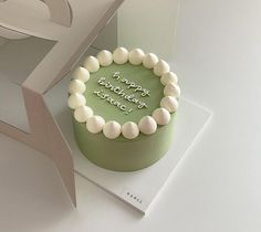 a green birthday cake with white frosting on top