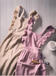 two dresses are laying next to each other on a table with utensils and spoons