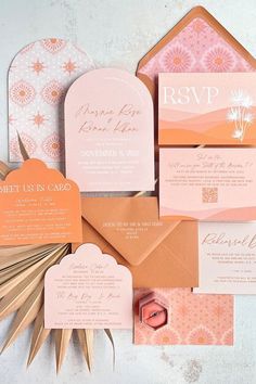 the wedding stationery is laid out on top of each other, including pink and orange