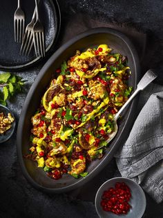 a pan filled with food on top of a table next to two plates and silverware