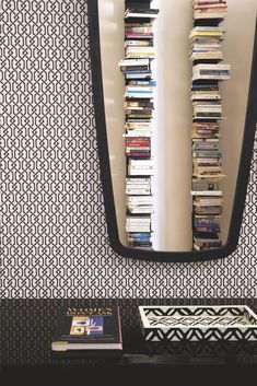 a black and white room with books on the shelf in front of a large mirror