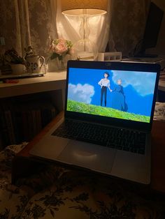 an open laptop computer sitting on top of a wooden desk in front of a lamp