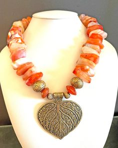 "Big, bold, orange and gold statement necklace Gorgeous huge orange carnelian sardonix agate wheel beads Gold Thai Khmer design beads Small brass beads Carnelian rondelles Bass leaf pendant (2-3/4\"L x 2-3/4\"W) Gold toggle clasp Length OA: 23\" #357 \"Orange Glow\"" Luxury Handmade Orange Necklace, Luxury Handmade Orange Necklaces, Luxury Spiritual Orange Necklace, Khmer Design, Orange Glow, Orange Carnelian, Orange Necklace, Brass Beads, Gold Statement Necklace