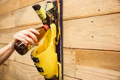 a person holding a beer bottle in front of a wall with skis on it