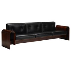 a black leather couch with wooden legs and arm rests against a white background, it appears to be in the style of art deco