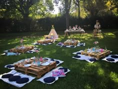 an outdoor picnic setting with wooden pallets and pillows on the grass in front of trees