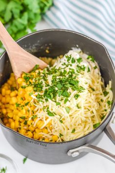 corn and parmesan in a pot with a wooden spoon