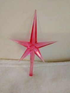 a pink plastic star sitting on top of a white blanket