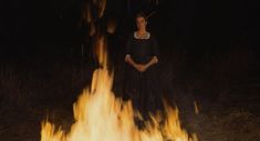 a woman standing in front of a fire