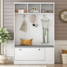 a white shelf with some clothes hanging on it and a clock in the back ground