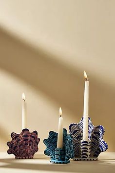 three candles sitting on top of each other in front of a white wall with shadows