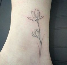 a single flower tattoo on the ankle is shown in black and grey ink, along with its delicate petals