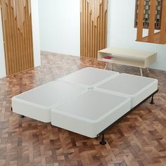 a bed sitting on top of a hard wood floor next to a white table and mirror