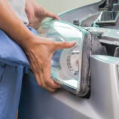 a person holding onto the headlight of a car