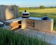 an outdoor bbq with grill and firewood