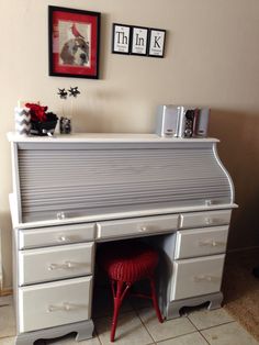 a white desk with two pictures on the wall above it and a red chair in front of it