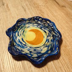 a blue and yellow bowl sitting on top of a wooden table