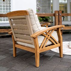 a wooden chair sitting on top of a brick floor next to a white rug and potted plant