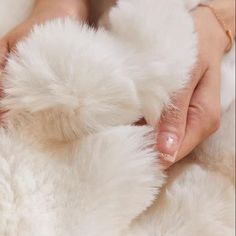 a person is holding a fluffy white animal's fur with their hands on it