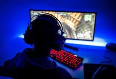 a person wearing headphones and sitting in front of a computer with a red keyboard