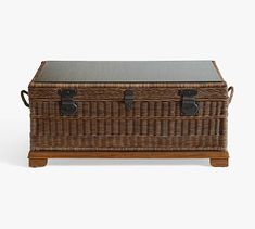 a wicker trunk with leather straps and handles on the top, sitting against a white background