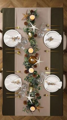 the table is set with white plates, silverware and pineconi wreaths