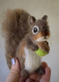 a stuffed squirrel holding a tennis ball in it's hand