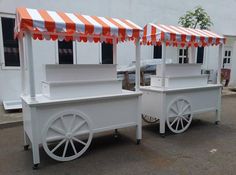 two white food carts with orange and white awnings