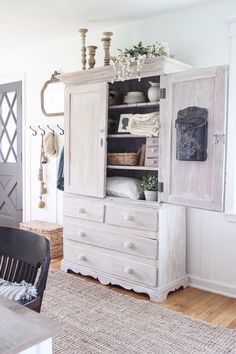 a room with a dresser, chair and table in it