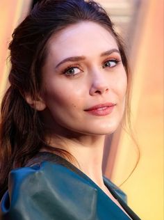 a close up of a person wearing a green leather jacket and orange lipstick on her lips