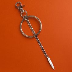 a metal keychain with a chain around it and a knife in the middle