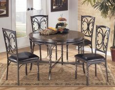 a dining room table with four chairs and a rug on the floor in front of it