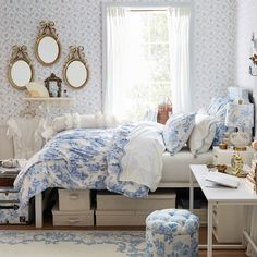 a bed room with a neatly made bed next to a desk and mirror on the wall